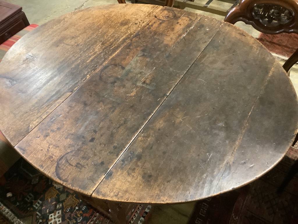 A mid 18th century oak oval topped gate leg dining table, fitted one drawer